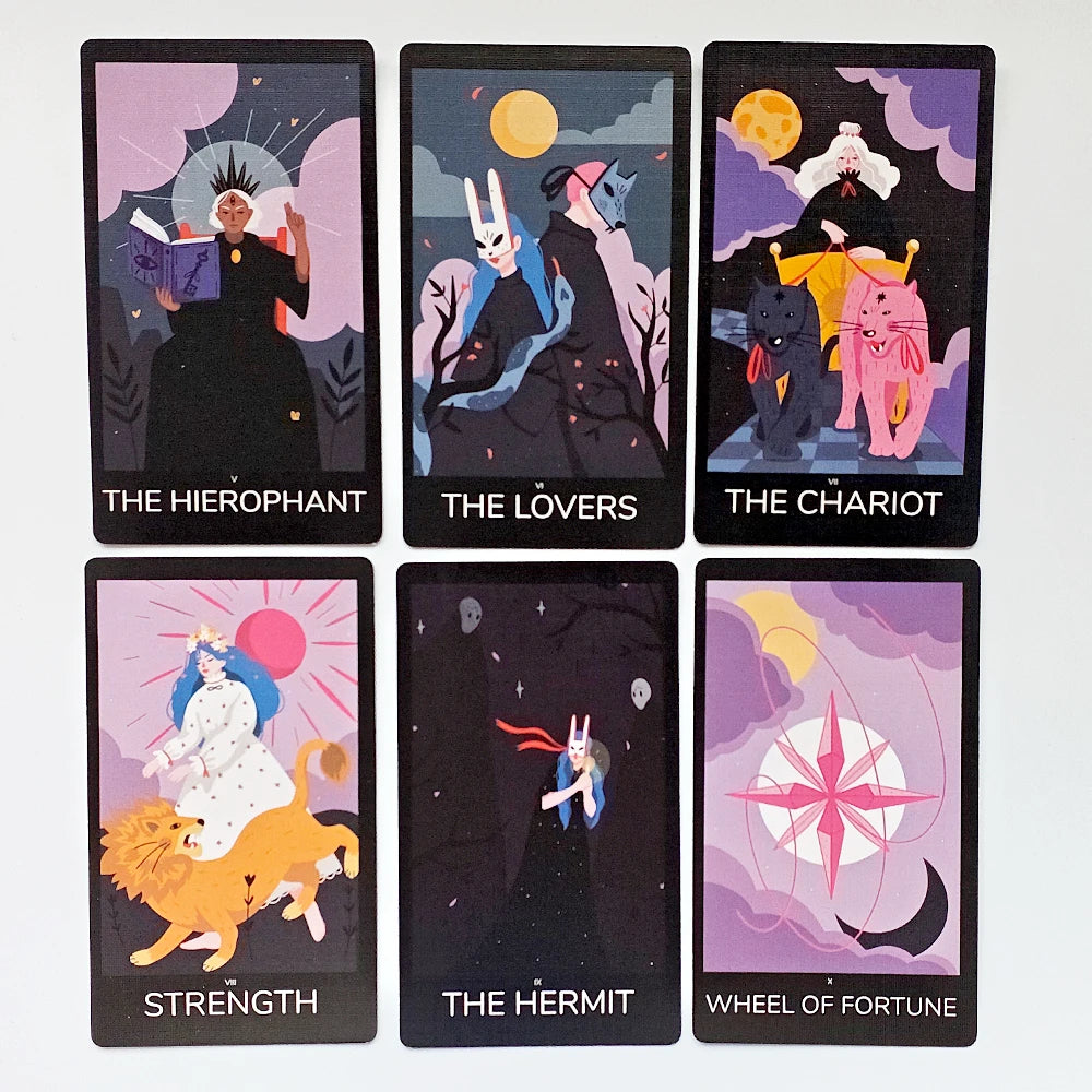 Sabotage Tarot — six Major Arcana face-up: V The Hierophant (spiked crown, spell book), VI The Lovers (rabbit-masked figures in moonlit forest), VII The Chariot (white-haired goddess with black and pink lions), VIII Strength (blue-haired figure with lion under pink sun), IX The Hermit (rabbit-masked figure falling through dark star-field), X Wheel of Fortune (pink compass rose with crescent moon)