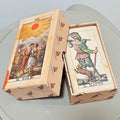 Tarocco Soprafino 1830 open tuck box with XIX Il Sole on lid (two figures beneath radiant red sun) showing Il Matto card on top of deck — bearded jester in colourful Renaissance dress with staff and dog; box wrapped in Il Meneghello ecru bat-print tissue