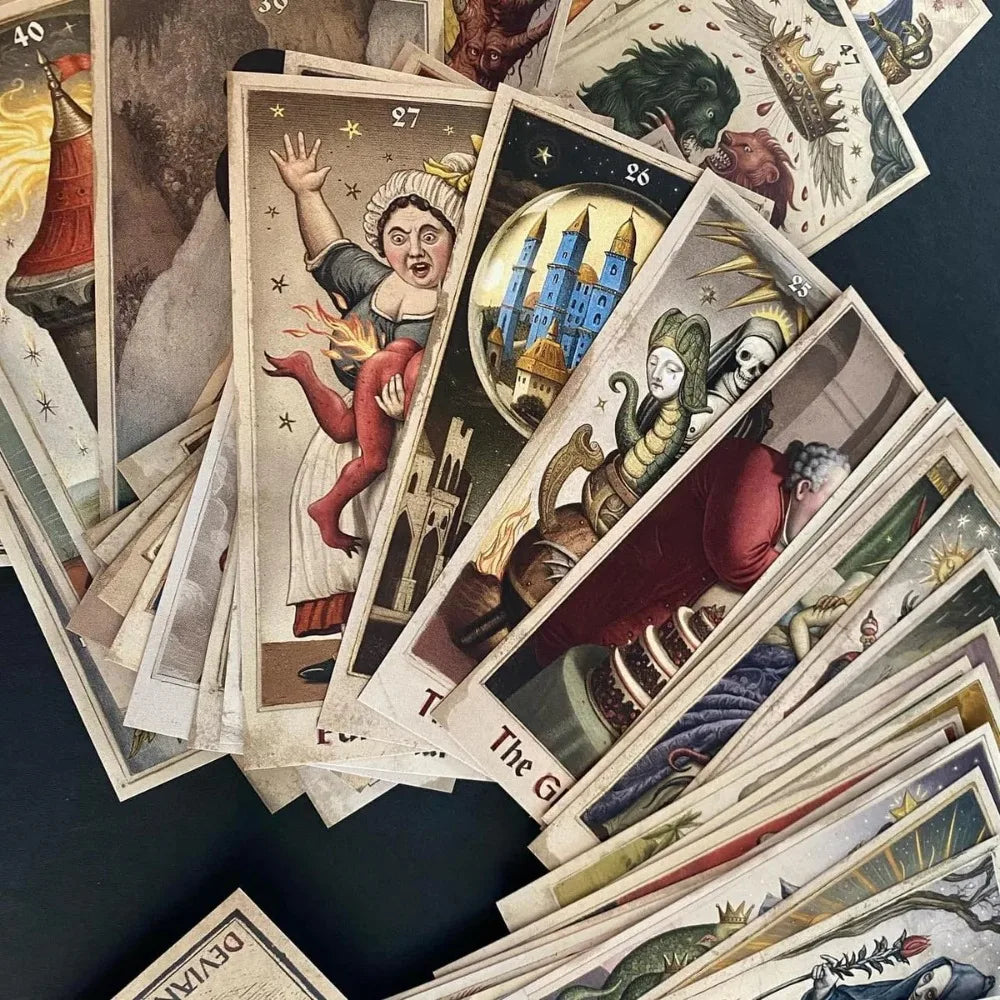The Zammer Twin’s Oracle — fan of cards face-up including card 27 (woman in medieval dress holding a flaming devil), card 26 (blue castle in a glass globe), and other numbered cards on dark surface