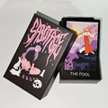 Sabotage Tarot matte black rigid box open showing full card deck with The Fool on top (red-haired figure at cliff edge with wand and white rabbit at sunrise); box lid shows bold pink psychedelic Sabotage lettering with kneeling figure, white rabbits and skull