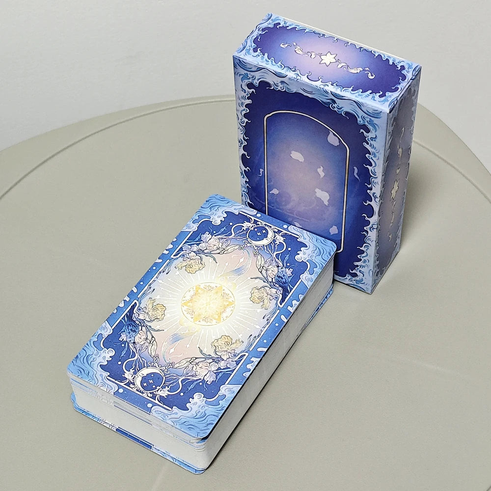 Silent Desolate Tarot — full deck showing blue celestial card backs with glowing sun medallion, Art Nouveau floral motifs and wave border; alongside the box rear panel showing a moonlit archway