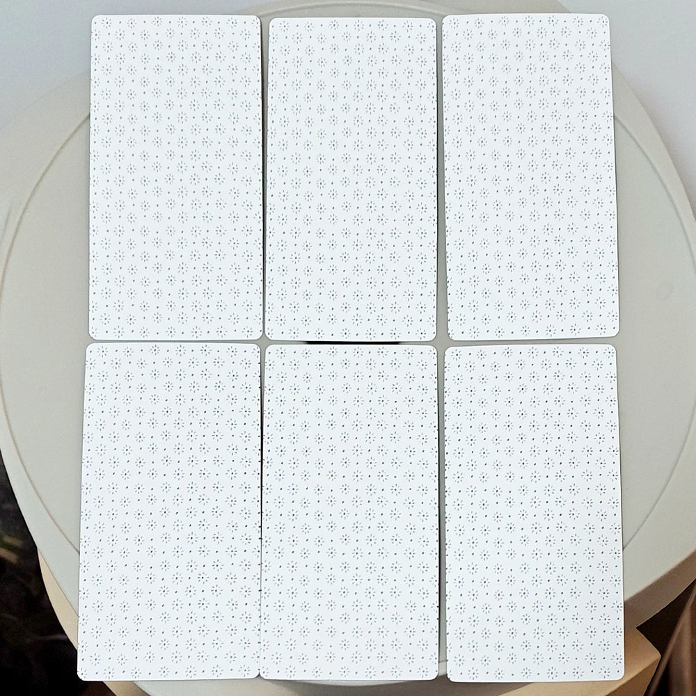 Tarocco Soprafino 1830 — six white card backs showing repeating small geometric snowflake/asterisk pattern on bright white ground; reversible design; shown on round white table